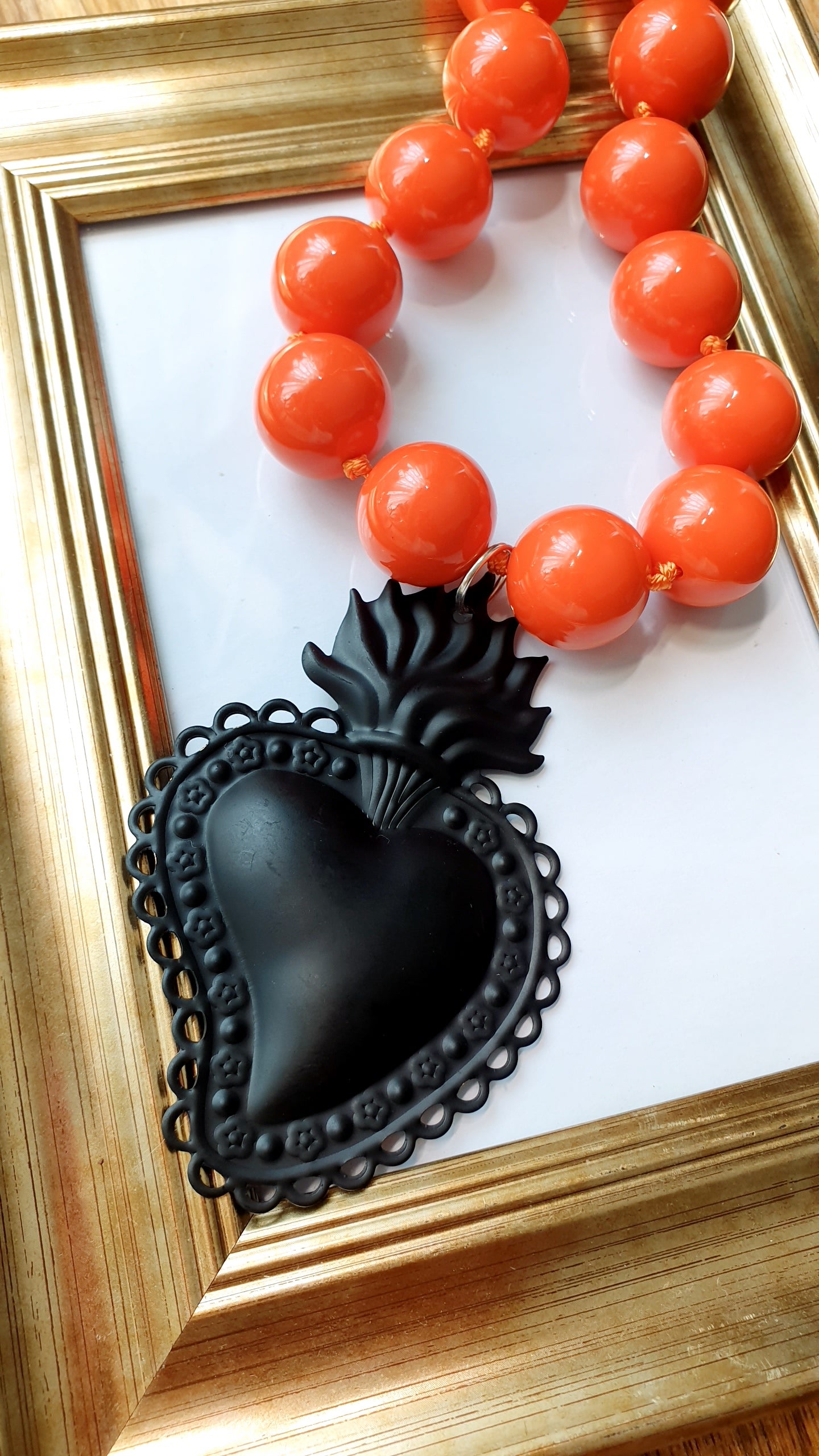 Girocollo in resina arancio con cuore sacro in metallo