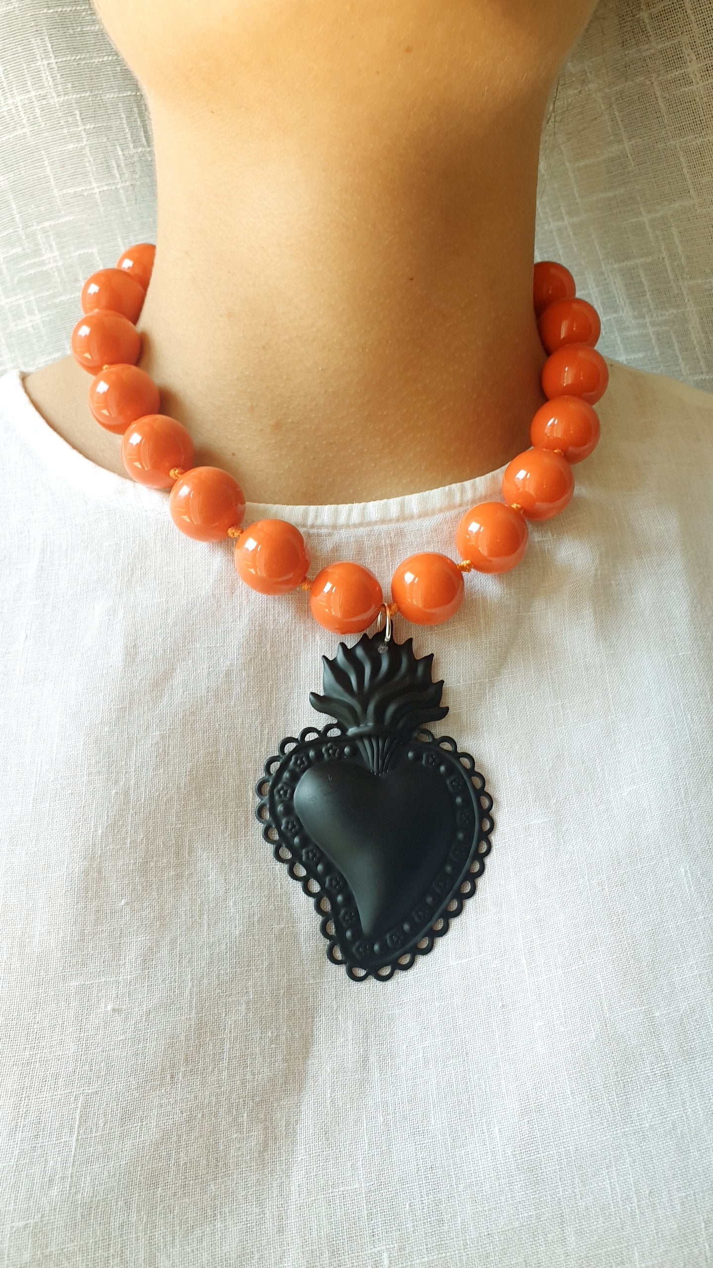 Girocollo in resina arancio con cuore sacro in metallo