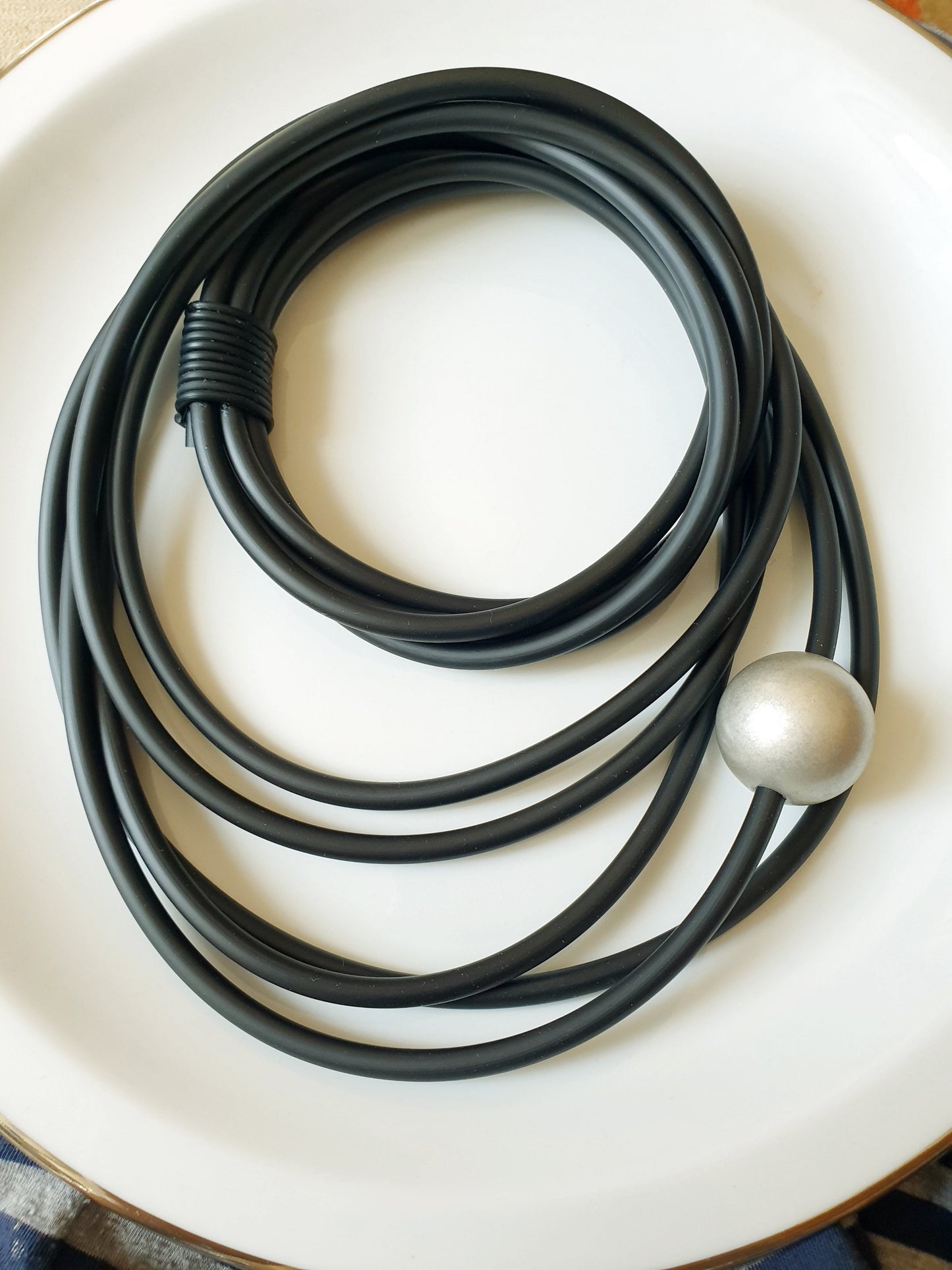Lunga collana in caucciù con sfera in resina.