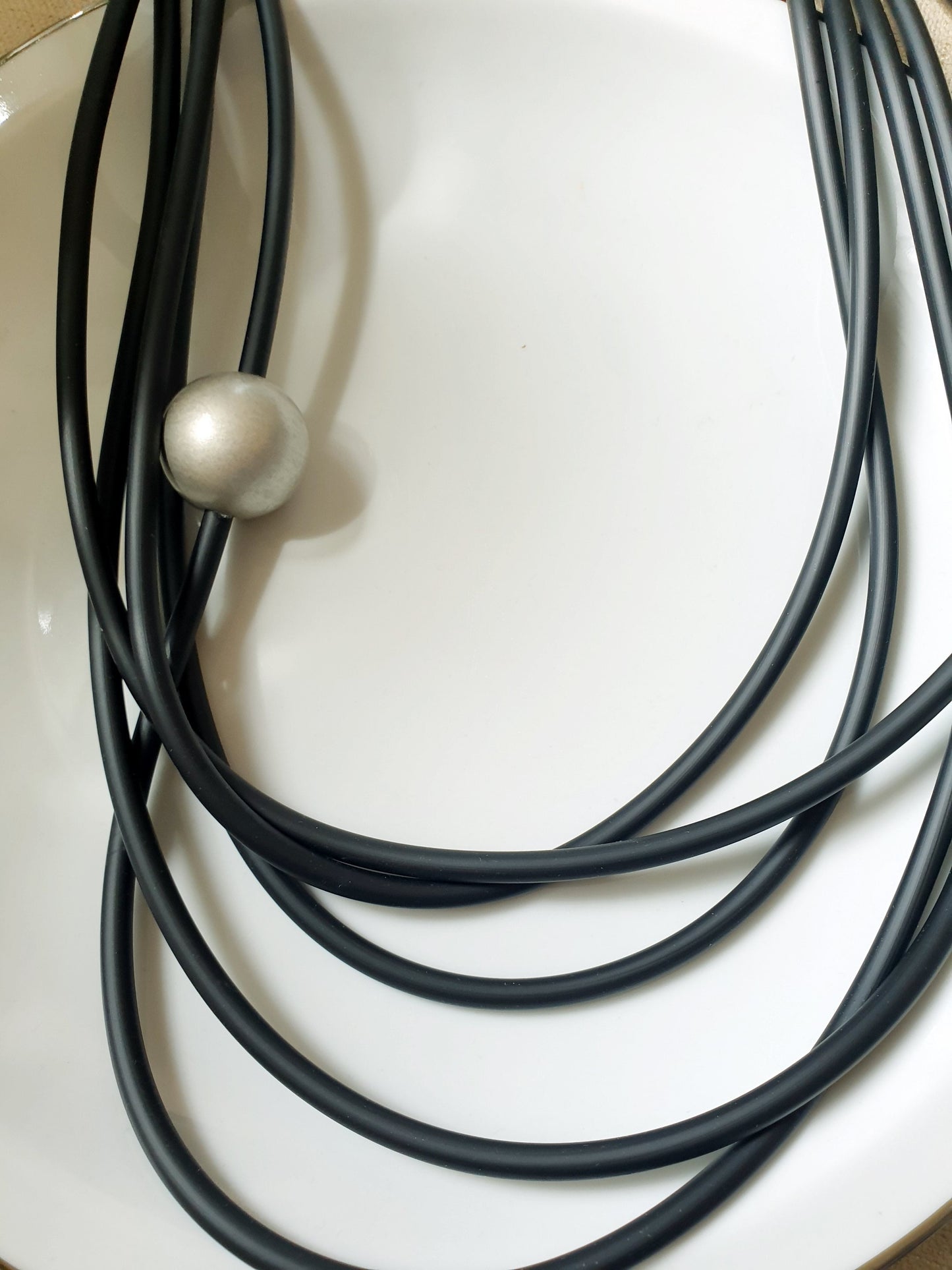 Lunga collana in caucciù con sfera in resina.