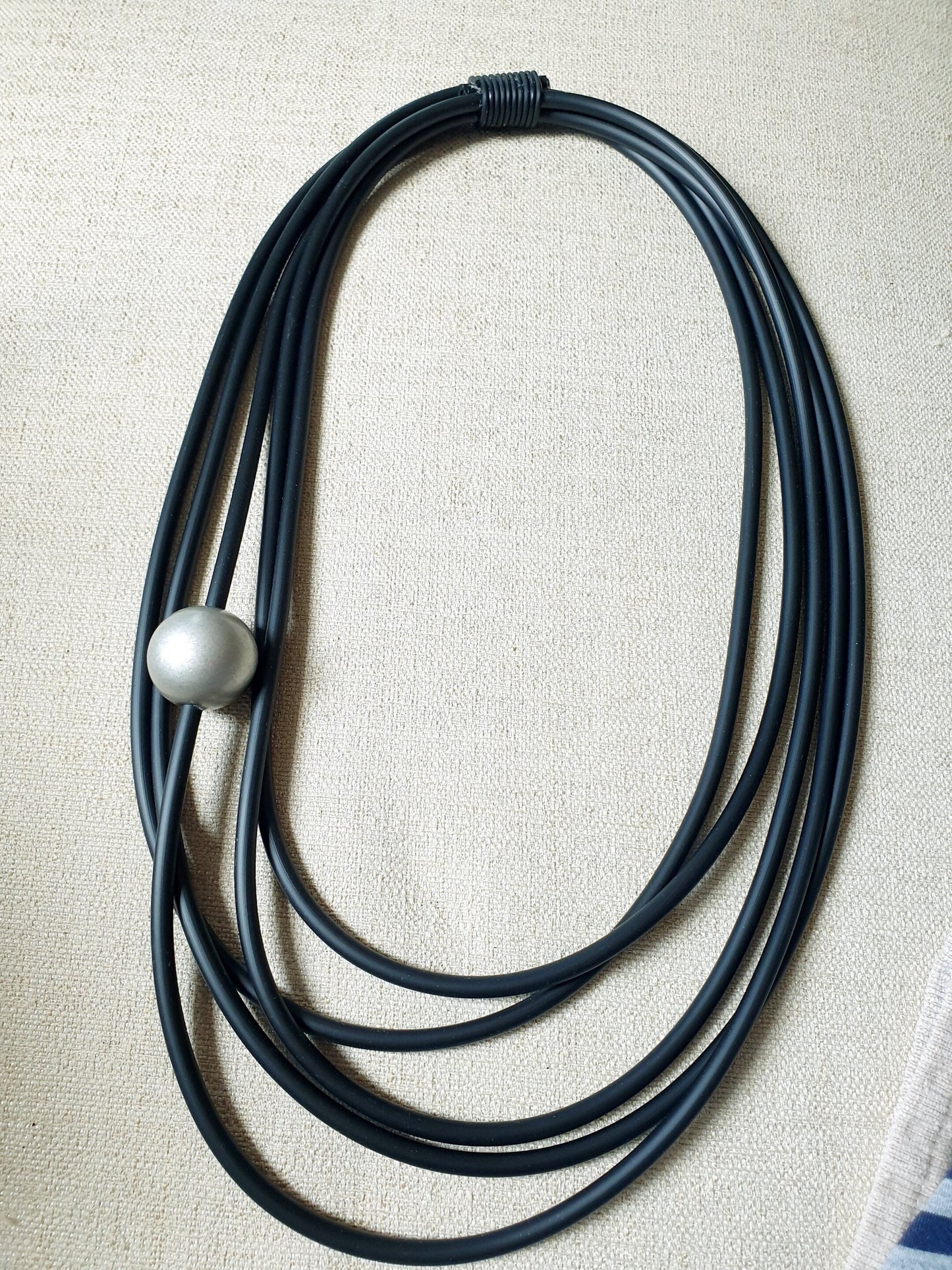 Lunga collana in caucciù con sfera in resina.