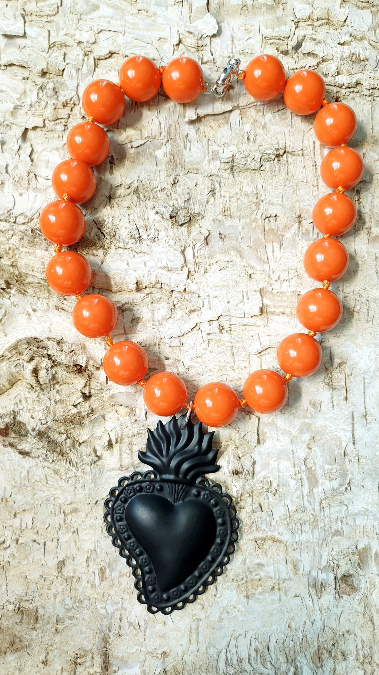 Girocollo in resina arancio con cuore sacro in metallo