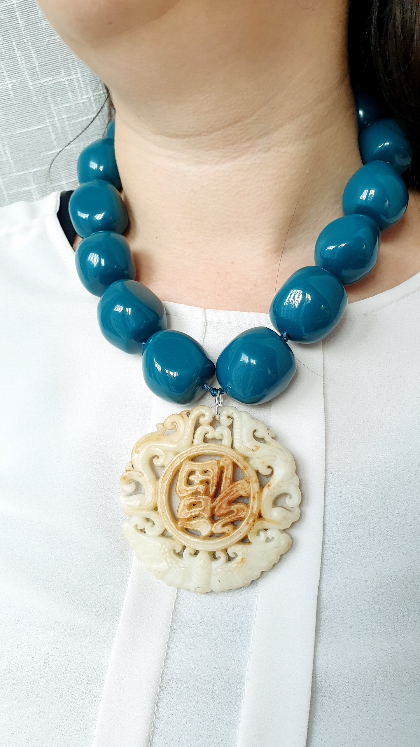 Collana in sfere di resina con giada intagliata.