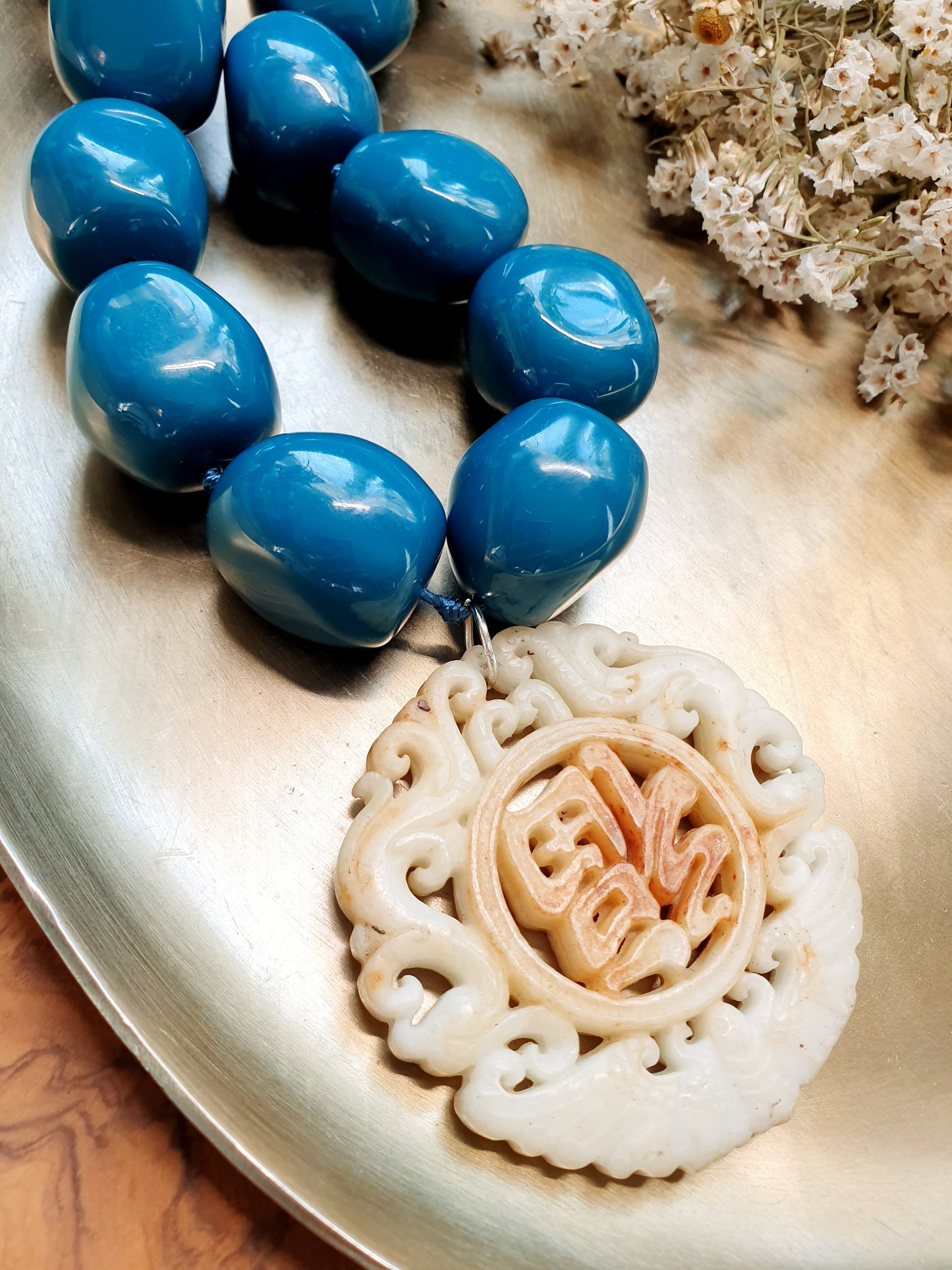 Collana in sfere di resina con giada intagliata.