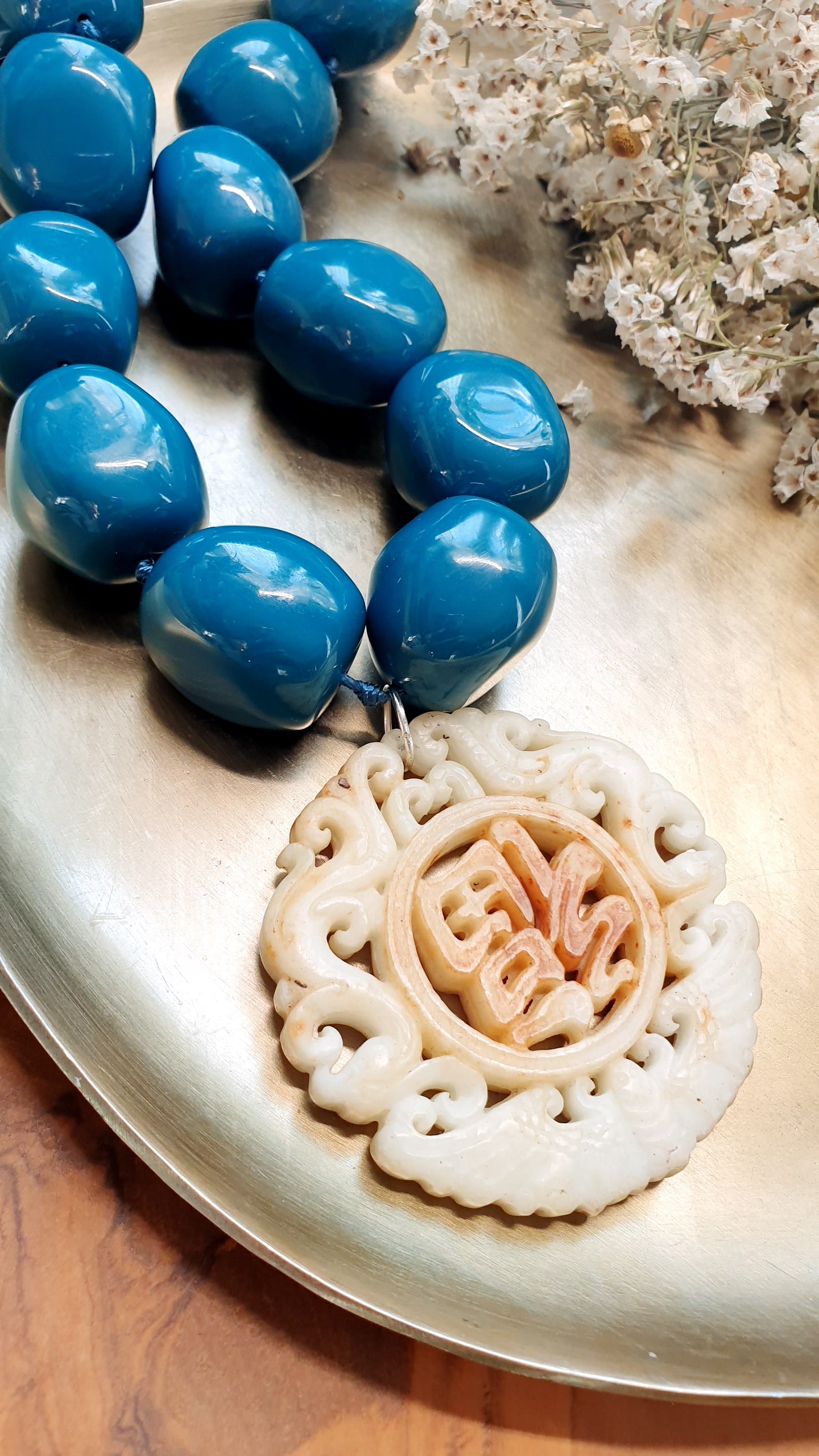 Collana in sfere di resina con giada intagliata.