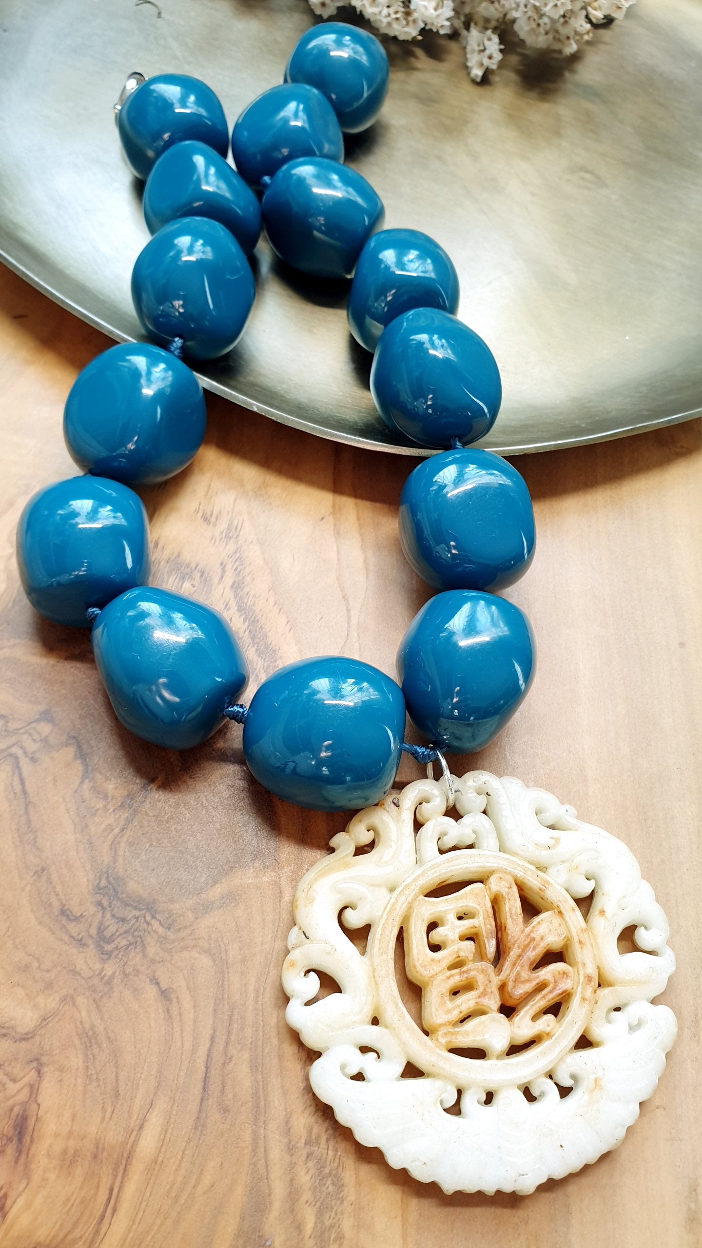 Collana in sfere di resina con giada intagliata.