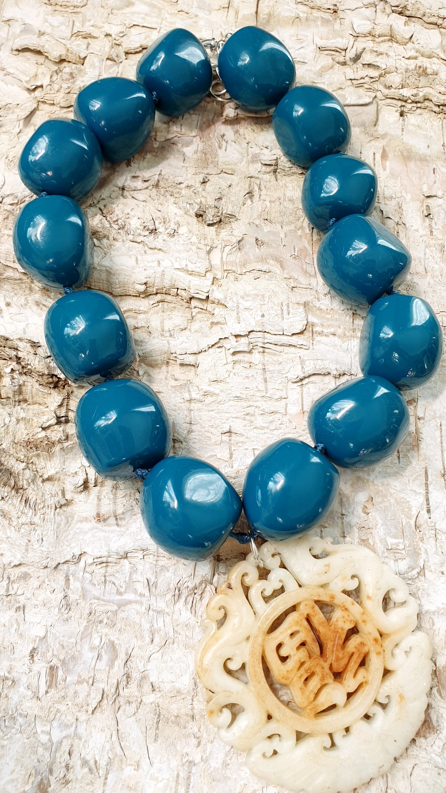 Collana in sfere di resina con giada intagliata.